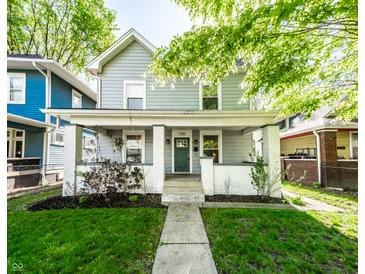 Charming two-story home boasts a welcoming front porch and well-maintained lawn with landscape at 1205 N Oxford St, Indianapolis, IN 46201