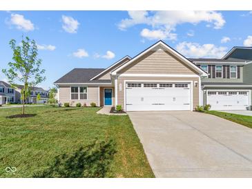 Tan home showcasing a blue front door, a two-car garage and a freshly landscaped yard at 2334 Black Rock Cir, Lebanon, IN 46052