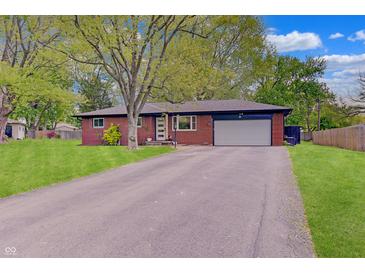 Charming brick home with an attached garage and mature trees accentuating the front lawn at 8049 Burn Ct, Indianapolis, IN 46217