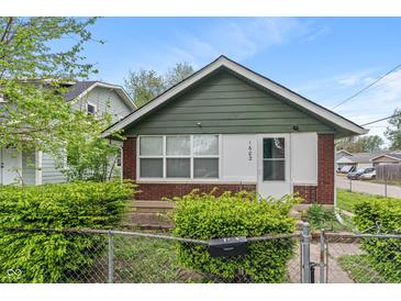 Charming single-story home with brick and green siding, fenced front yard, and bright natural light at 1602 Villa Ave, Indianapolis, IN 46203