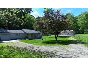 Charming home featuring a well-maintained lawn and a gravel driveway, surrounded by mature trees at 3282 S Conservation Club Rd, Morgantown, IN 46160