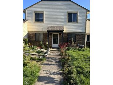 Charming home exterior with brick accents and lush greenery in the front yard at 4984 W 59Th St, Indianapolis, IN 46254