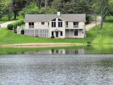 Charming lakefront home with large windows, inviting deck, and lush green lawn at 515 E Hoover Dr, Nineveh, IN 46164