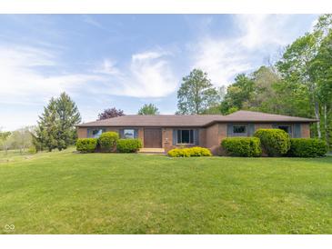Charming single-story brick home featuring well-maintained landscaping and a lush green lawn at 8292 E 100 S, Greenfield, IN 46140