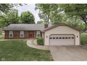 Charming single-story home features a brick facade, attached garage, and mature trees in the front yard at 912 Ramblin Rd, Greenwood, IN 46142