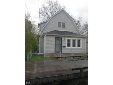 Charming two-story home featuring vinyl siding, well-maintained lawn, and a secure chain-link fence at 1433 Charles St, Indianapolis, IN 46225