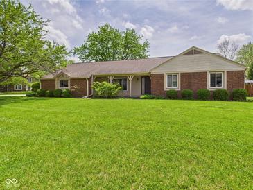 Ranch style home with brick and siding, a covered porch, and a large front yard with mature shade trees at 1645 Woodview Ln, Anderson, IN 46011