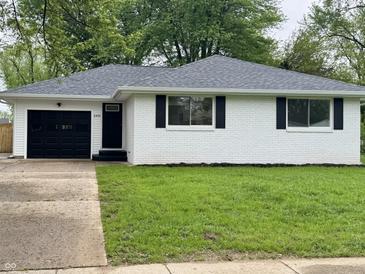 Charming white brick home with black shutters, complemented by a well-maintained lawn and black garage door at 2431 Timbercrest Dr, Columbus, IN 47203