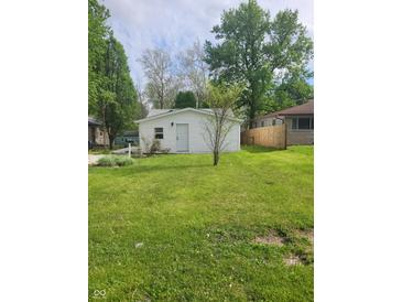 White sided home with green grass and mature trees in the background at 2855 Walker Ave, Indianapolis, IN 46203