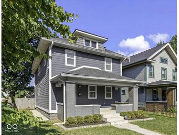Charming two-story home with gray siding, white trim, a welcoming front porch, and well-manicured landscaping at 2940 N Park Ave, Indianapolis, IN 46205