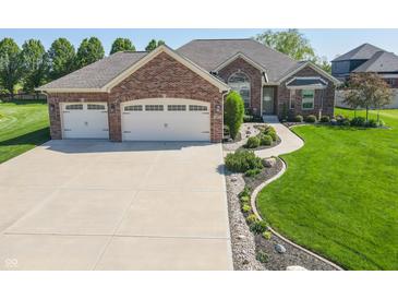 Beautiful brick home featuring a three-car garage, manicured lawn, and appealing landscaping at 6077 W David Wayne Dr, New Palestine, IN 46163