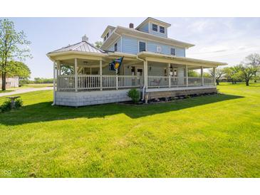 Charming two-story home showcasing a spacious wrap-around porch and lush green lawn at 9579 N Fortville Pike, Fortville, IN 46040