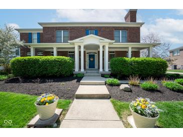 Charming red brick home with covered front porch, blue door, and well-manicured landscaping at 1787 Halifax St, Carmel, IN 46032