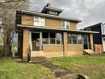 Two-story brick home featuring a quaint front porch and well-maintained lawn at 3443 Broadway St, Indianapolis, IN 46205