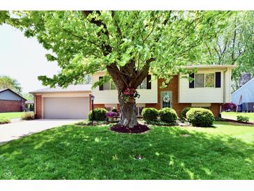 Charming split-level home boasts a lush front yard with mature tree and well-manicured landscaping at 5225 Elderberry Rd, Noblesville, IN 46062