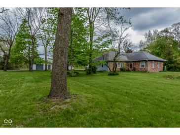 Charming brick home with well-maintained lawn, mature trees and a detached garage, offering serene countryside living at 8944 W 21St St, Indianapolis, IN 46234