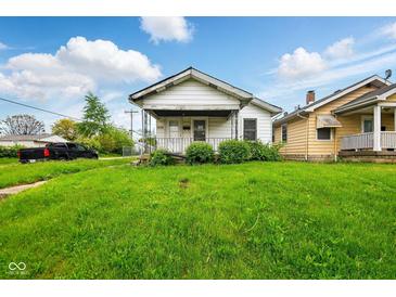 Quaint one-story home featuring a well-maintained lawn and inviting front porch at 1235 N Grant Ave, Indianapolis, IN 46201