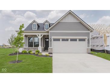 Charming single-Gathering home with gray siding, a two-car garage and a well manicured front yard at 13324 Roundtop Rd, Noblesville, IN 46060
