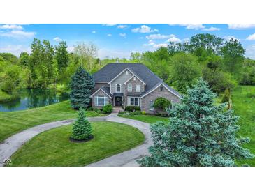 Stunning two-story brick home with lush landscaping, circular drive, and a serene pond in the backyard at 1933 S 825 E, Zionsville, IN 46077
