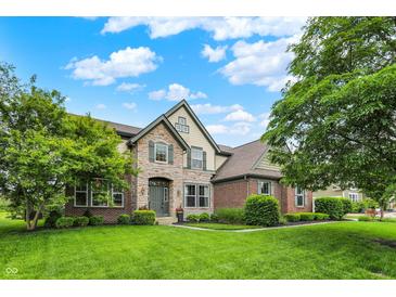 Charming two-story home featuring a stone and brick facade, lush lawn, and mature trees at 9179 Brookstone Pl, Zionsville, IN 46077