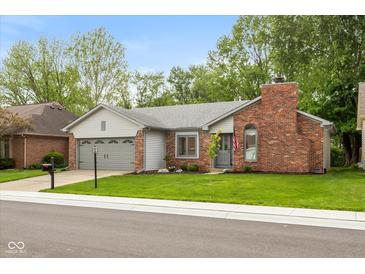 Charming single-story home with a brick chimney, gray siding, well-maintained lawn, and an attached two-car garage at 12290 Charing Cross Rd, Carmel, IN 46033