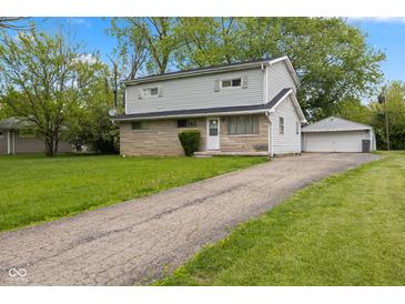 Two-story home featuring stone accents, light gray siding, a detached garage, and a paved driveway at 3425 N Elizabeth St, Indianapolis, IN 46226