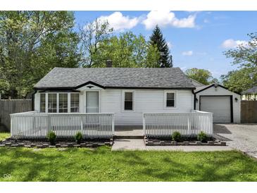 Charming single-story home with a white picket fence, lush green lawn, and detached garage at 4721 E Morris St, Indianapolis, IN 46203