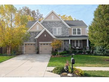 Charming two-story home with a three-car garage, manicured lawn, and a mix of stone and brick facade at 665 Featherstone Dr, Westfield, IN 46074