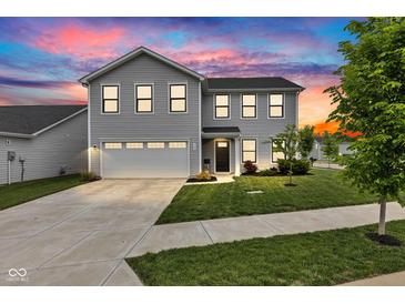 Beautiful two-story home featuring a well-manicured lawn and attached two-car garage, illuminated by a vibrant sunset at 900 Sunchaser Rd, Lebanon, IN 46052