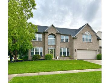 Charming two-story brick home with a green lawn, a two-car garage, and a beautifully landscaped front yard at 1454 Woodfield Dr, Greenwood, IN 46143