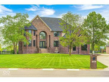 Majestic brick home featuring a well-manicured lawn and a charming water fountain at 16285 Remington Dr, Fishers, IN 46037