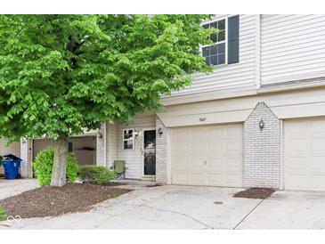 Charming townhouse featuring a one-car garage, lovely landscaping, and cozy front porch at 7045 Gavin Dr, Indianapolis, IN 46217