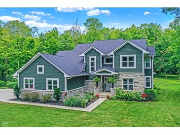 Beautiful two-story home with stone accents and landscaped front yard on a sunny day at 7716 Traders Hollow Ln, Indianapolis, IN 46278