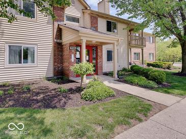Inviting condo featuring a red front door, well-maintained landscaping, and a charming brick and siding exterior at 1098 Timber Creek Dr # 2, Carmel, IN 46032