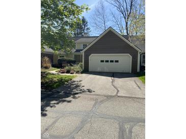 Home exterior featuring an attached garage, yellow siding, and well-maintained landscaping at 1915 Seaport Dr, Indianapolis, IN 46240