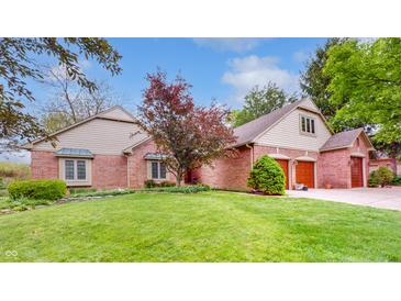 Charming brick home featuring an attached two car garage, manicured lawn, and mature trees at 265 Monticello Dr, Greenwood, IN 46142