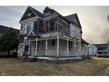 Two story home with covered front porch in need of some TLC and exterior paint at 802 S Anderson St, Elwood, IN 46036