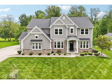 Beautiful two-story home with a stone and siding exterior, lush green lawn, and manicured landscaping at 9155 Kerwood Dr, Indianapolis, IN 46240