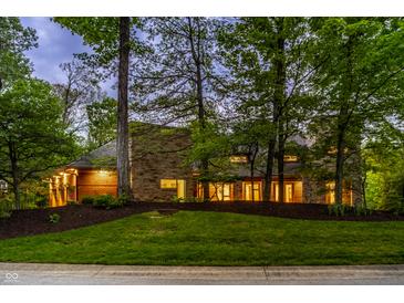Stunning stone home with lush landscaping and mature trees providing privacy and curb appeal at 9387 Sullivan Pl, Zionsville, IN 46077