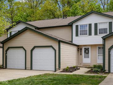 Charming townhome features a two-car garage, neutral siding, green trim, and a well-manicured lawn at 9493 Timber View Dr, Indianapolis, IN 46250