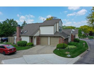 Traditional two-story home featuring a brick chimney, attached two-car garage, and manicured front lawn at 11614 Buttonwood Dr, Carmel, IN 46033