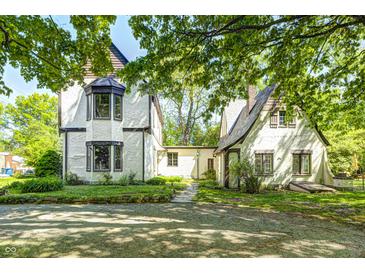 Charming exterior view of a Tudor-style home with white stucco and lush greenery at 4302 Kessler Blvd N Dr, Indianapolis, IN 46220