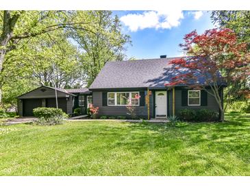 Charming home with a well-manicured lawn, dark siding, and mature trees creating a welcoming curb appeal at 5721 Daphne Dr, Indianapolis, IN 46278