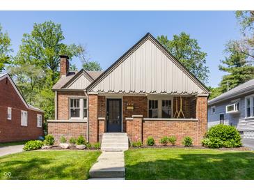 Charming brick home featuring a symmetrical design, covered porch, manicured lawn, and classic architectural details at 5912 Evanston Ave, Indianapolis, IN 46220