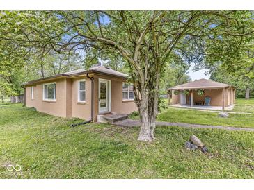 Charming exterior view of a brick house and patio, shaded by a large tree in a lush green yard at 6401 N Oakland Ave, Indianapolis, IN 46220