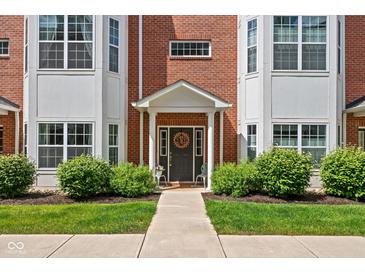 Charming home featuring a welcoming front door, brick facade, manicured lawn, and lush landscaping at 863 N Park Trail Dr, Carmel, IN 46032
