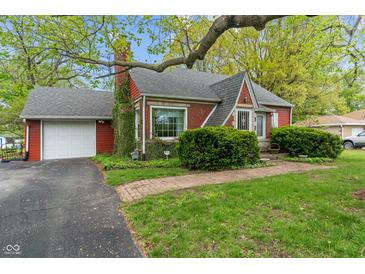 Charming red brick home featuring a well-manicured lawn and a detached garage at 8636 Rockville Rd, Indianapolis, IN 46234