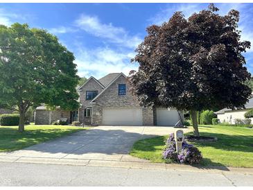 Well-maintained brick house with a three-car garage, mature trees, and a sunny sky above at 941 W Barouche, Pendleton, IN 46064