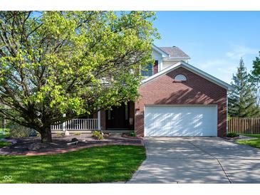 Charming two-story brick home with attached garage and landscaped front yard, partially shaded by a large tree at 9910 Suncoral Cir, Fishers, IN 46038