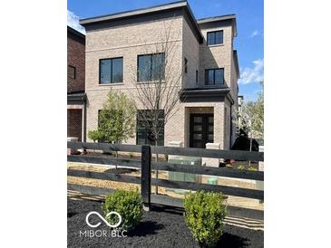 Modern brick home featuring a well-manicured yard and black fence at 11904 Spring Mill Rd, Carmel, IN 46032